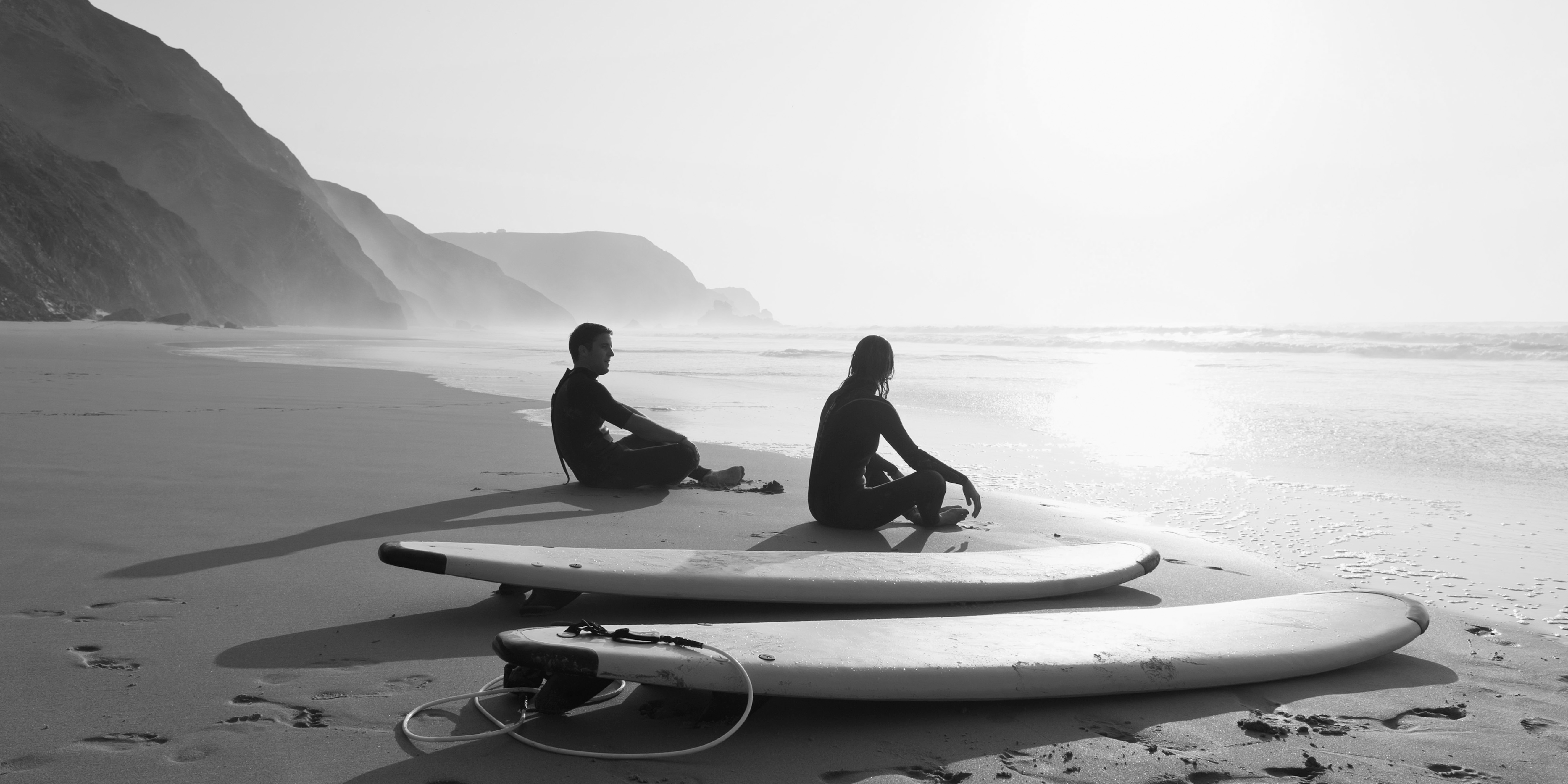 portugal-couple-sitting-on-beach-by-surfboard-2022-12-16-22-19-09-utc