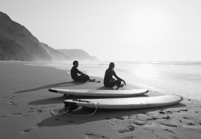 portugal-couple-sitting-on-beach-by-surfboard-2022-12-16-22-19-09-utc